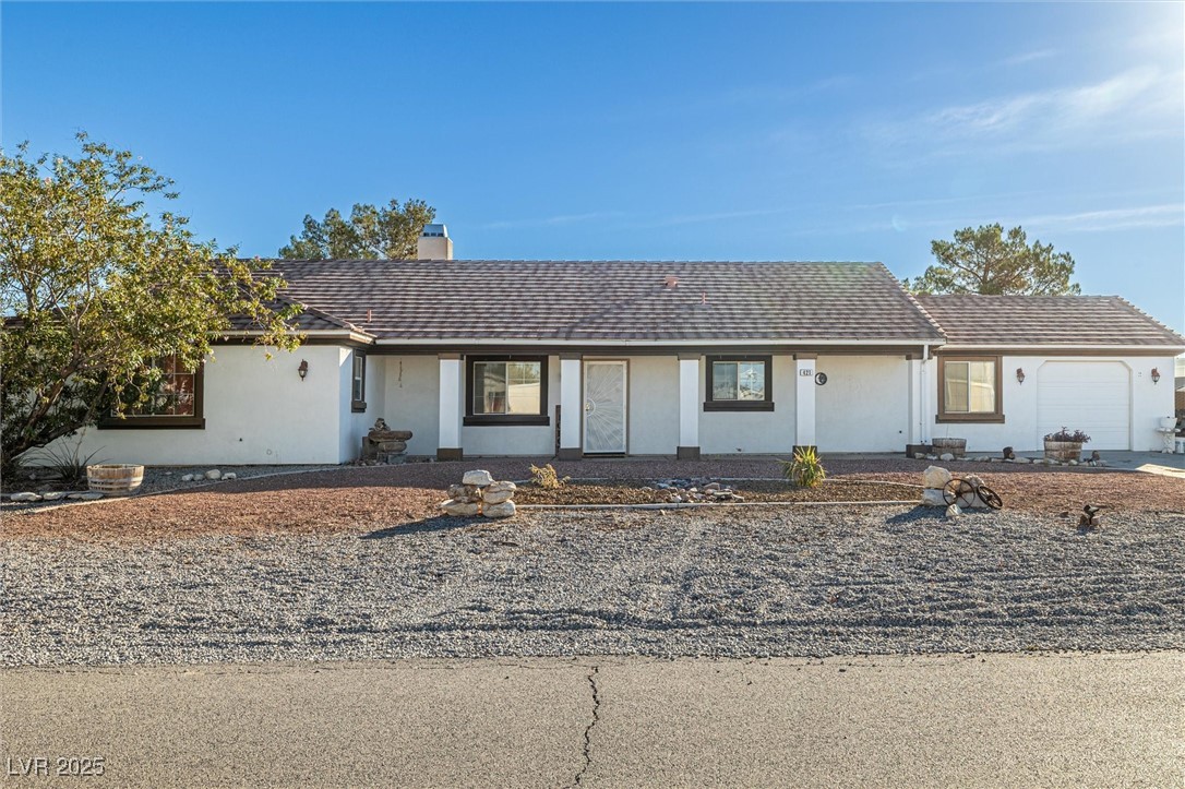 Ranch-style home featuring stucco siding, a garage, a chimney, and covered porch