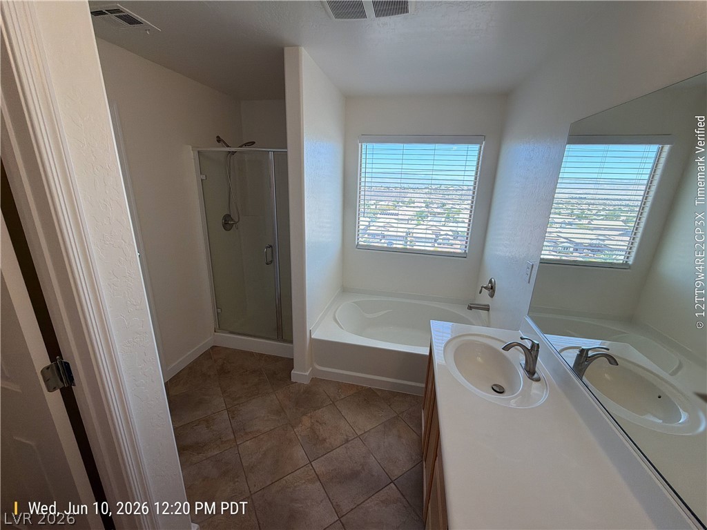 2388 Rue Bienville Way Henderson, NV 89044 - Photo 10 of 16 Step into a well-lit bathroom featuring a clean vanity, soaking tub, and enclosed shower.