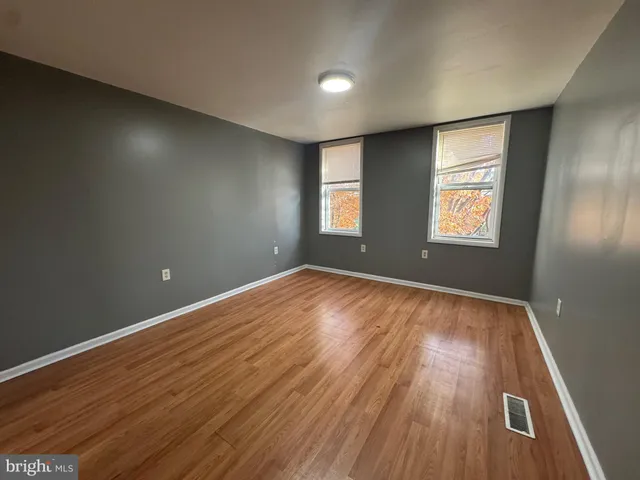 an empty room with wooden floor and windows