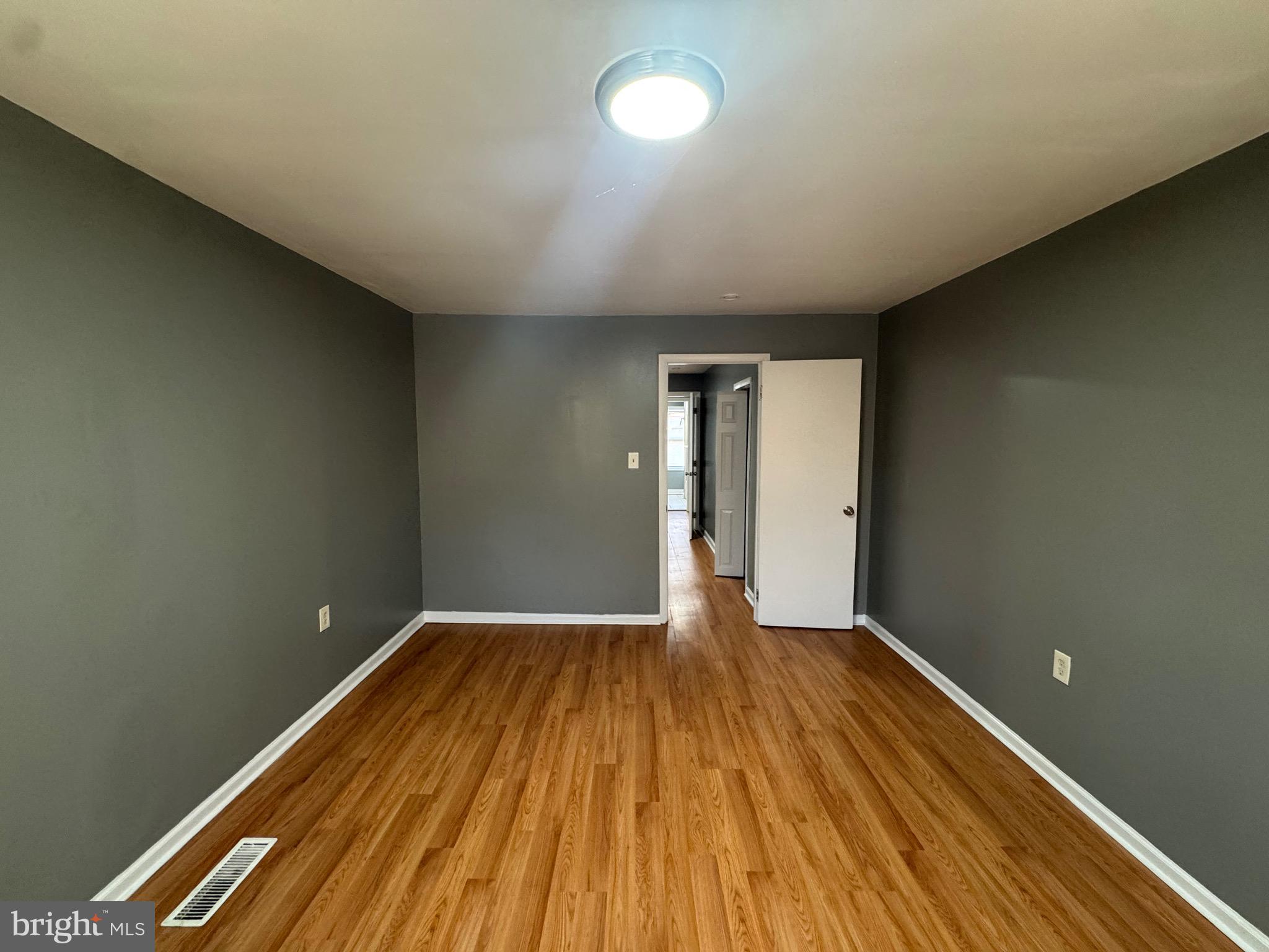 2408 Wilkens Avenue Baltimore, MD 21223 - Photo 7 of 26 a view of an empty room with wooden floor and a window