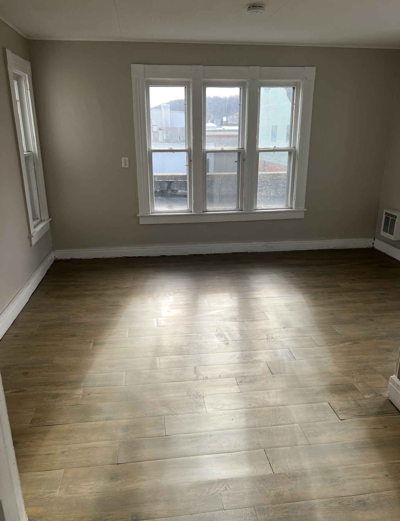 an empty room with wooden floor and windows