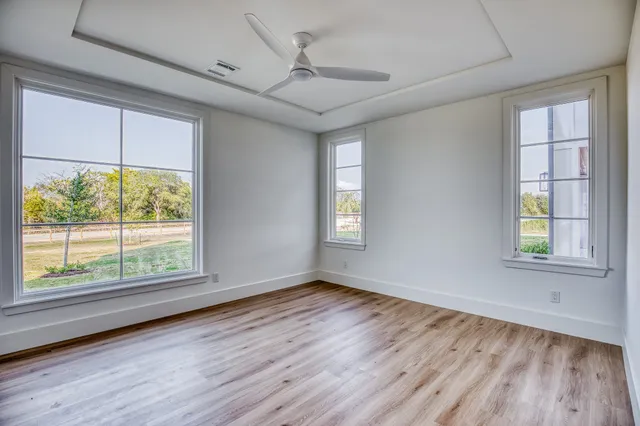a view of empty room with wooden floor and fan