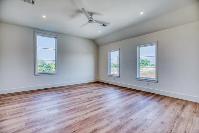 a view of an empty room with a window and wooden floor