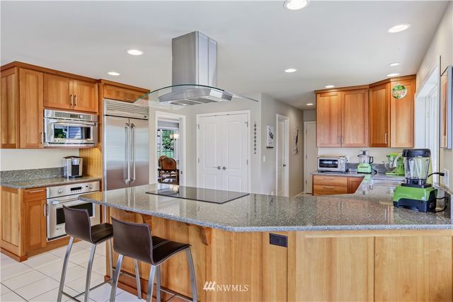 a kitchen with stainless steel appliances granite countertop a stove a refrigerator a oven a sink with island and chairs