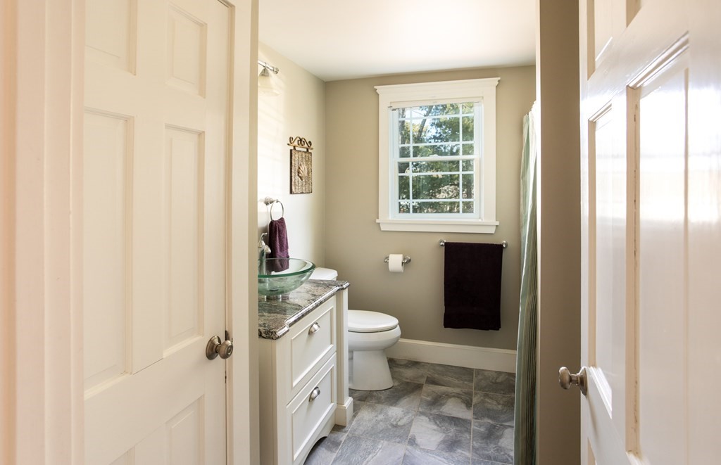 40 Bay Cotuit, MA 02635 - Photo 13 of 24 a bathroom with a granite countertop toilet a sink a mirror and a shower