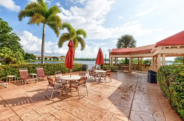 a view of a patio with a table and chairs under an umbrella with potted plants