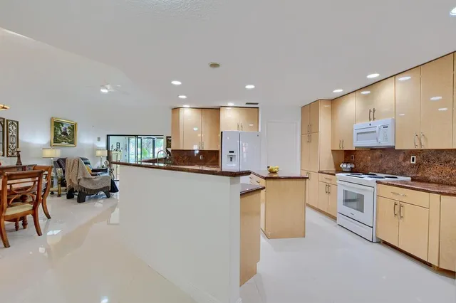 a kitchen with stainless steel appliances kitchen island granite countertop a stove top oven a sink a dining table and chairs