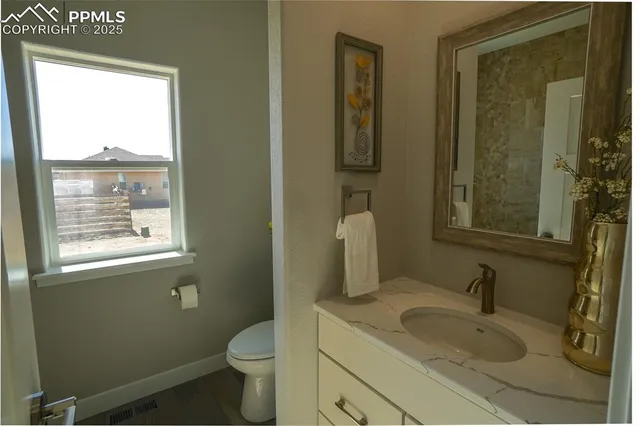 a bathroom with a granite countertop sink toilet and mirror