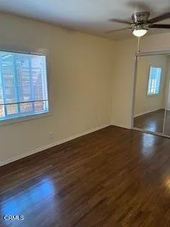 an empty room with wooden floor fan and windows