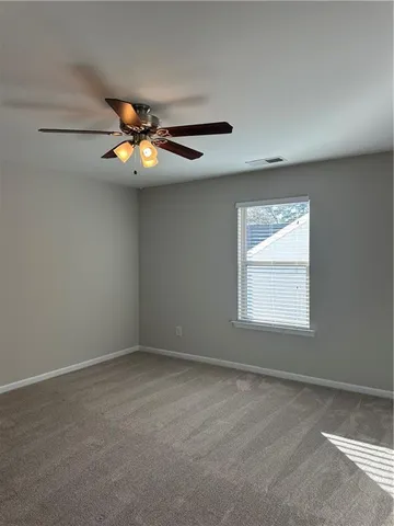 an empty room with a chandelier fan and windows