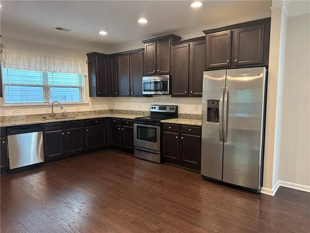 a kitchen with kitchen island granite countertop stainless steel appliances and wooden cabinets