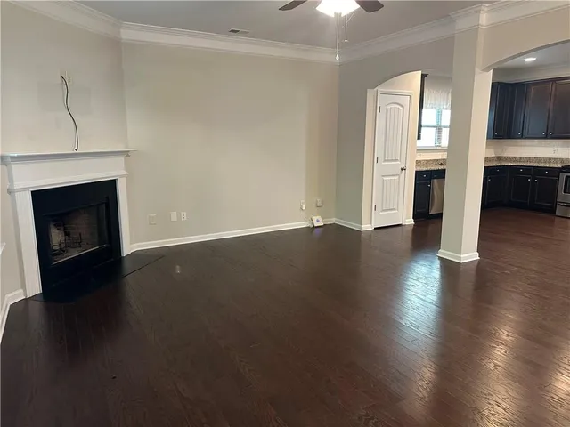 an empty room with wooden floor fireplace and windows