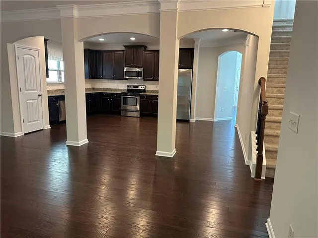 a view of a hallway with wooden floor windows and a kitchen