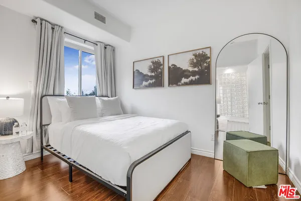 a bedroom with a bed and dresser with wooden floor