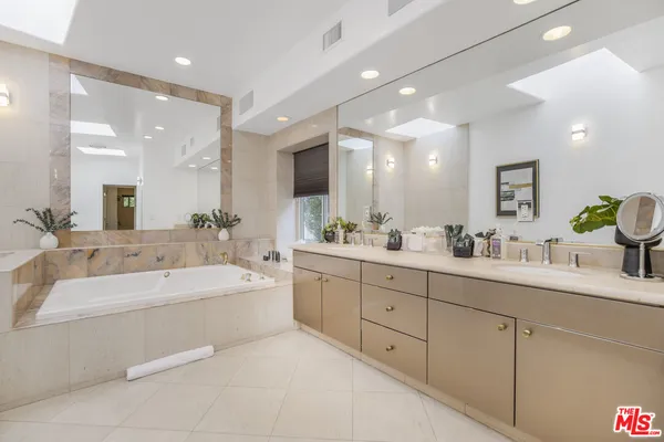 a bathroom with a double vanity sink mirror and bathtub