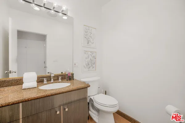 a bathroom with a granite countertop sink toilet and a mirror