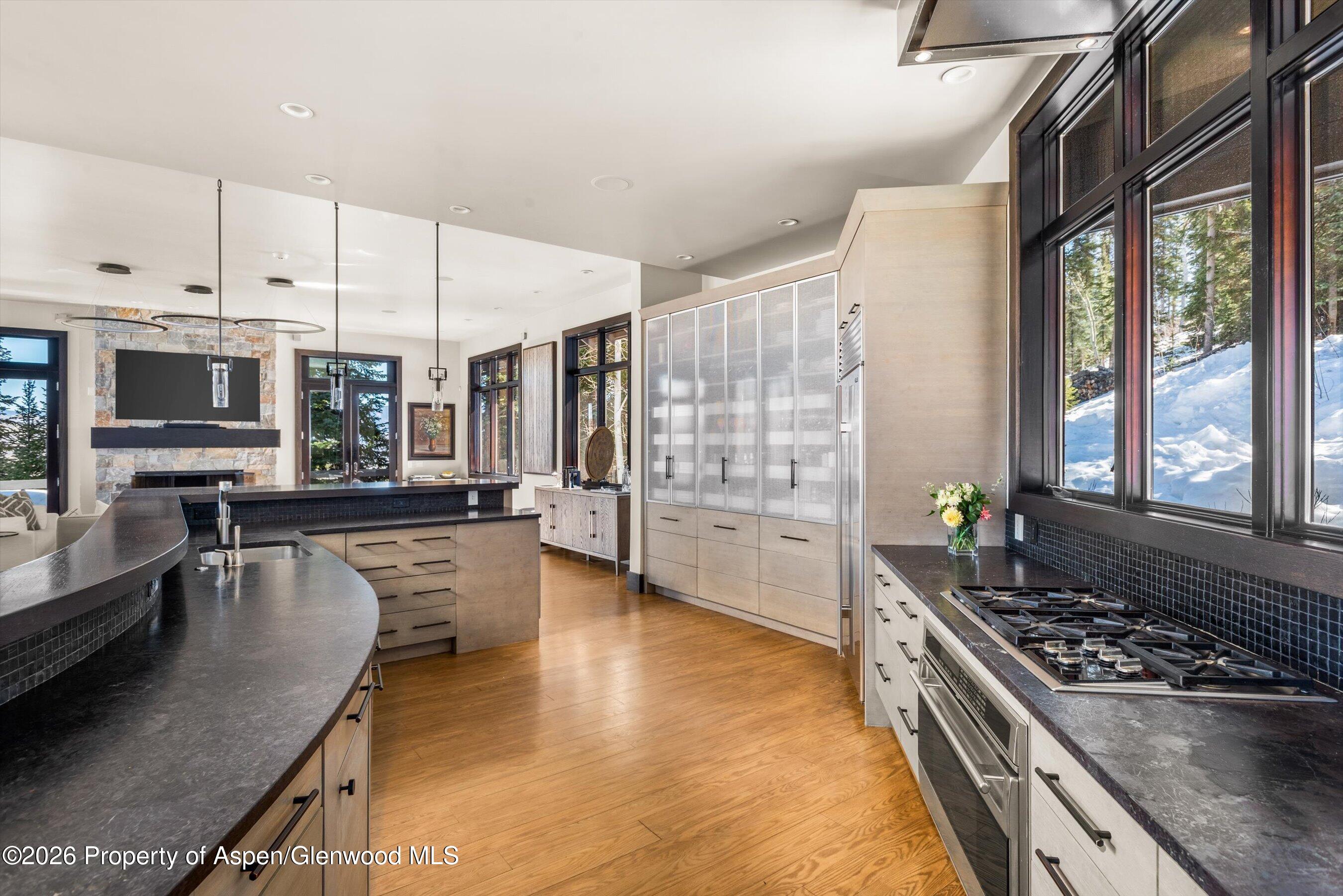 32 Elk Ridge Lane Snowmass Village, CO 81615 - Photo 18 of 58 a kitchen with stainless steel appliances granite countertop a stove top oven a sink dishwasher a dining table and chairs with wooden floor
