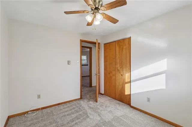 an empty room with closet and a chandelier fan