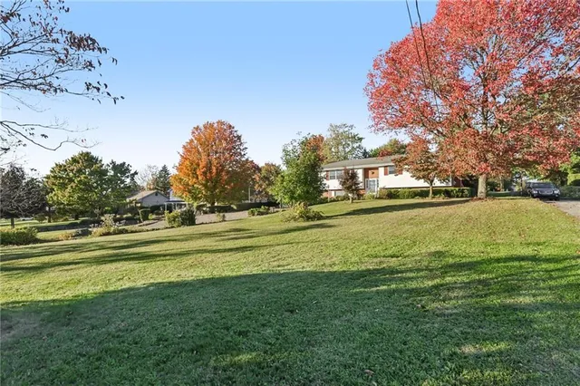 a view of a house with a big yard and large trees