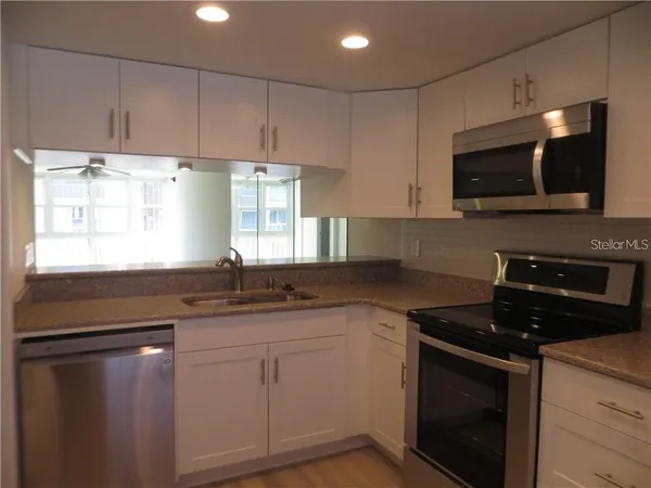 a kitchen with granite countertop white cabinets and a stove