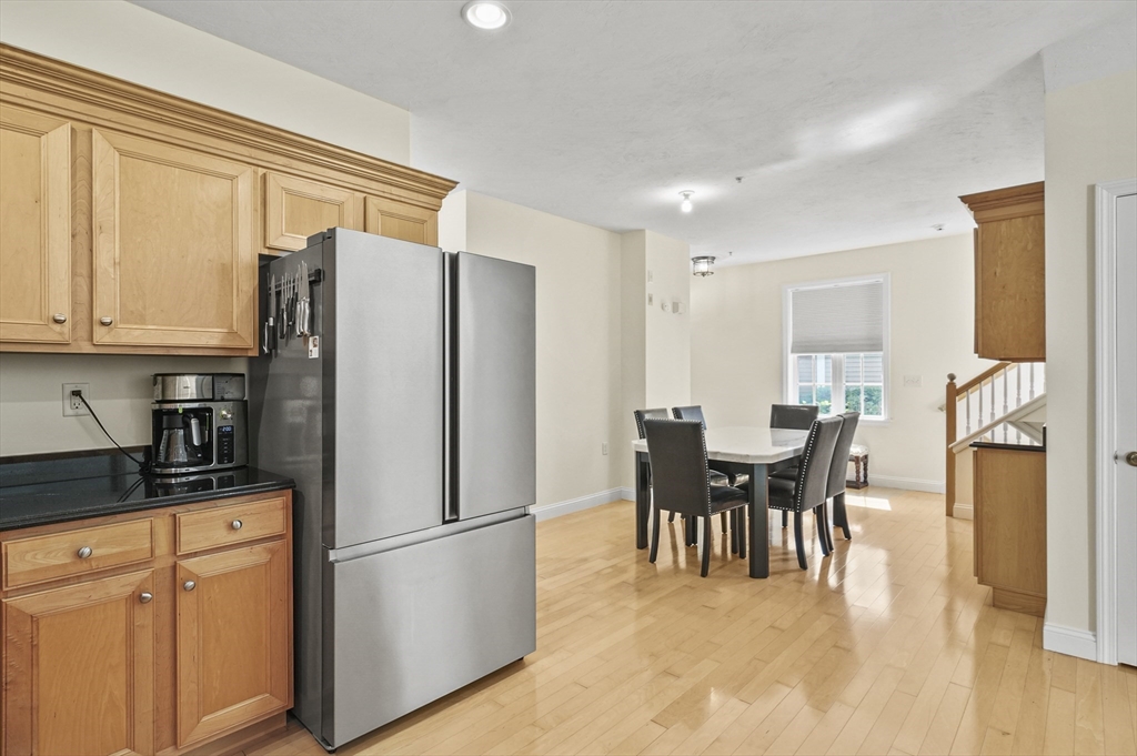 508 Linwood Court, Unit 508 Clinton, MA 01510 - Photo 14 of 32 a kitchen with stainless steel appliances granite countertop a refrigerator a sink a dining table and chairs with wooden floor