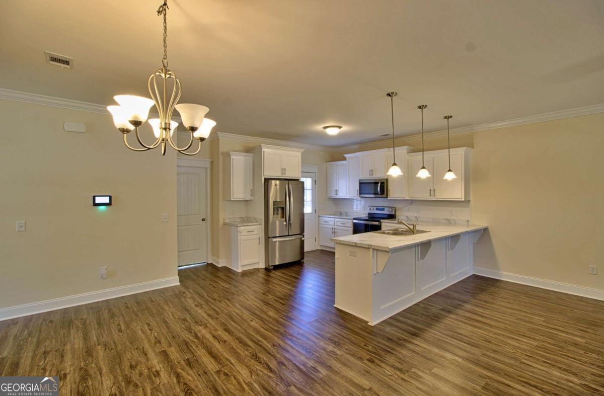 455 Bluff Road Jesup, GA 31545 - Photo 4 of 22 a kitchen with stainless steel appliances granite countertop a sink stove and a wooden floor