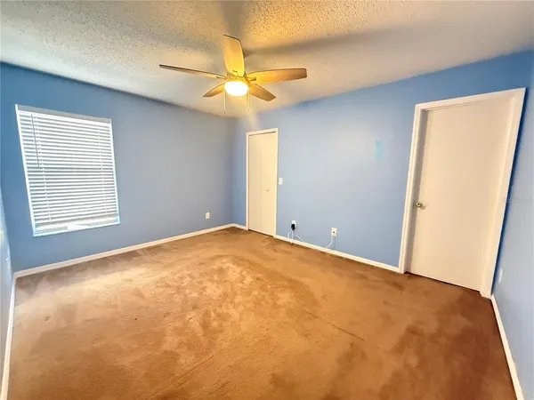 an empty room with a chandelier fan and windows