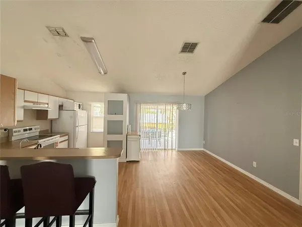 a living room with stainless steel appliances wooden floor dining table and chairs