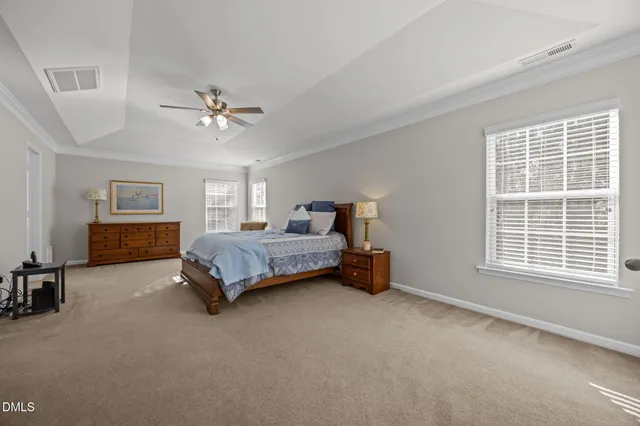 a spacious bedroom with a bed a chandelier and a window