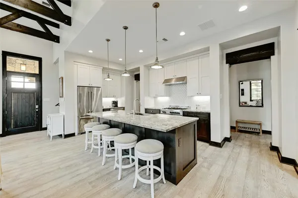 a kitchen with stainless steel appliances kitchen island granite countertop a table chairs and a refrigerator