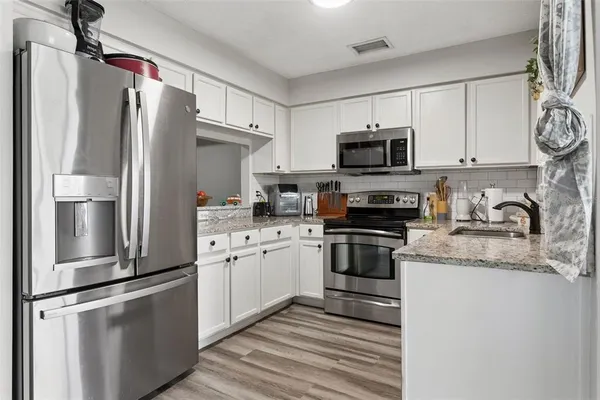 a kitchen with stainless steel appliances granite countertop a refrigerator sink and microwave