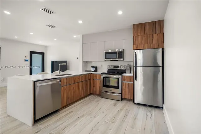 a kitchen with sink a refrigerator and white cabinets