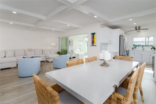 a large living room with stainless steel appliances kitchen island granite countertop a dining table chairs and a large window