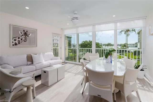 a living room with furniture large windows and wooden floor