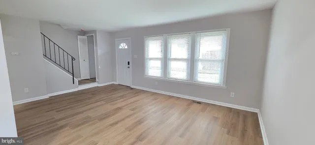 a view of an empty room with wooden floor and stairs
