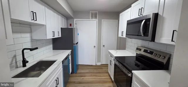 a kitchen with a refrigerator sink and cabinets
