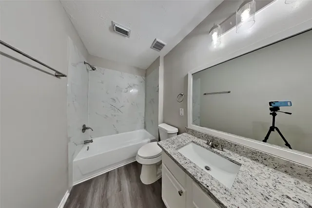 a bathroom with a granite countertop sink toilet and shower