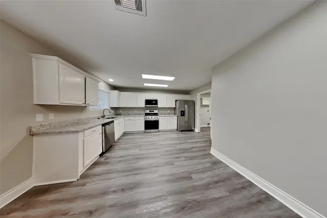 a large kitchen with white cabinets stainless steel appliances