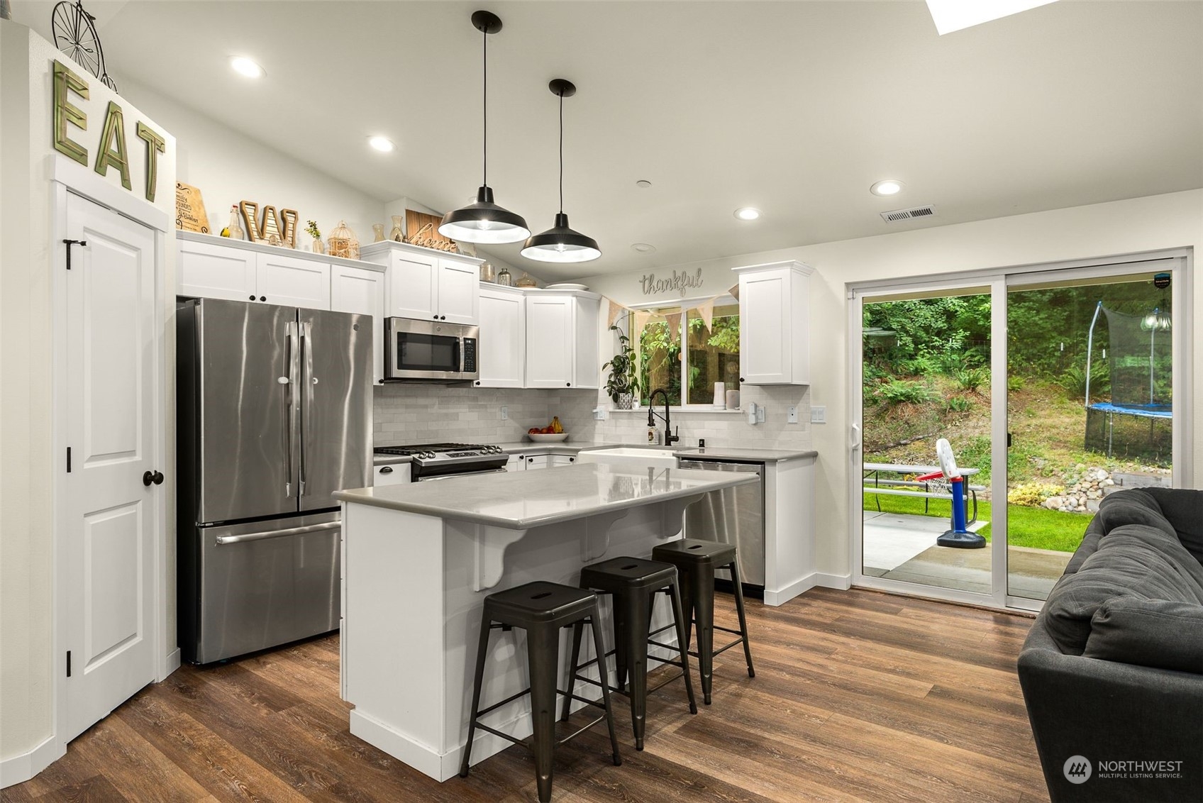 9924 Angeline Road East Bonney Lake, WA 98391 - Photo 8 of 31 a kitchen with stainless steel appliances granite countertop a refrigerator a sink dishwasher a stove and a dining table with wooden floor