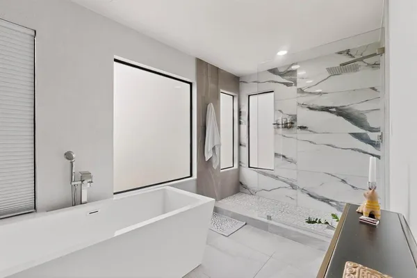 a bathroom with a tub a sink and a large mirror