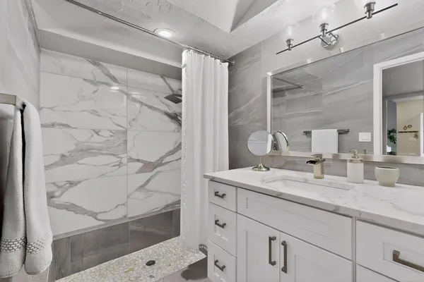 a bathroom with a granite countertop sink a mirror and shower