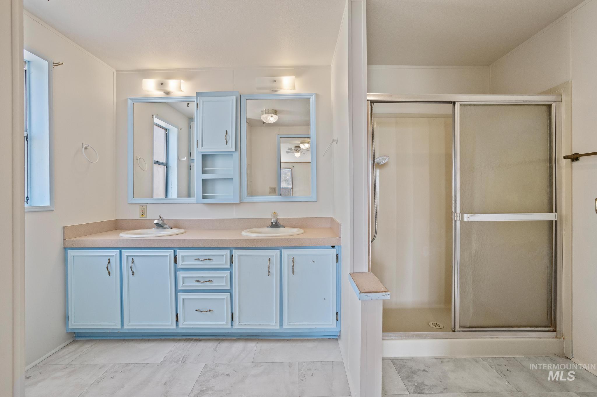 3680 South Mill Road Emmett, ID 83617 - Photo 29 of 38 Bathroom featuring a dual vanity with light blue cabinetry and integrated sinks set in a light-toned countertop