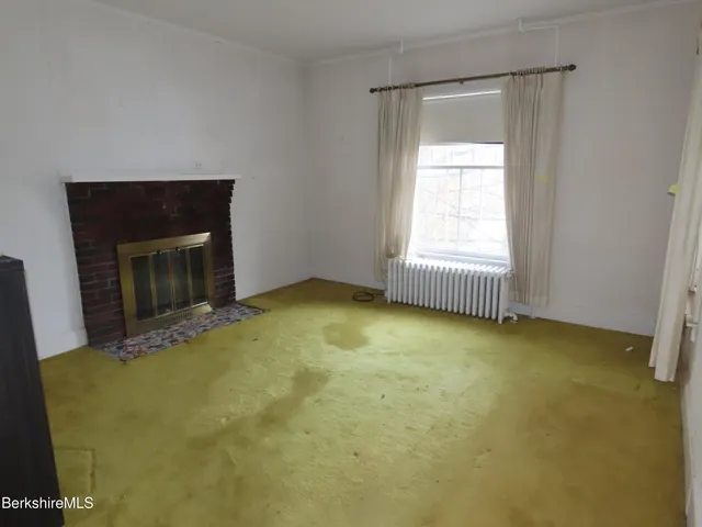 a view of an empty room with a fireplace and a window