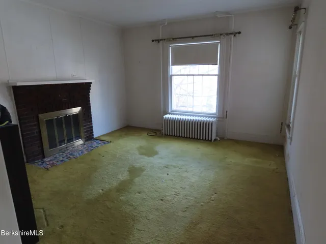 a view of an empty room with a fireplace and a window