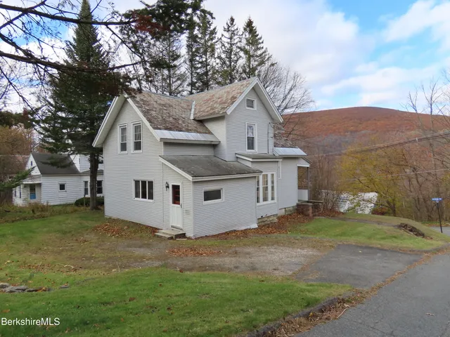 a view of a yard in front of a house with a large tree
