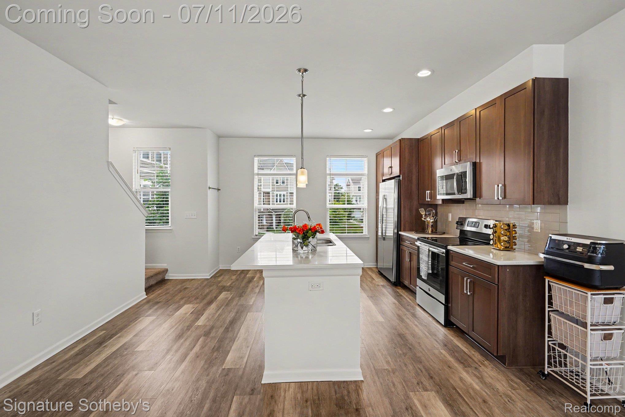 2500 Normandy Road, Unit 40 Royal Oak, MI 48073 - Photo 9 of 26 Modern kitchen featuring an island with a white countertop, recessed lighting, wood-finish flooring, dark wood cabinetry, and stainless steel appliances