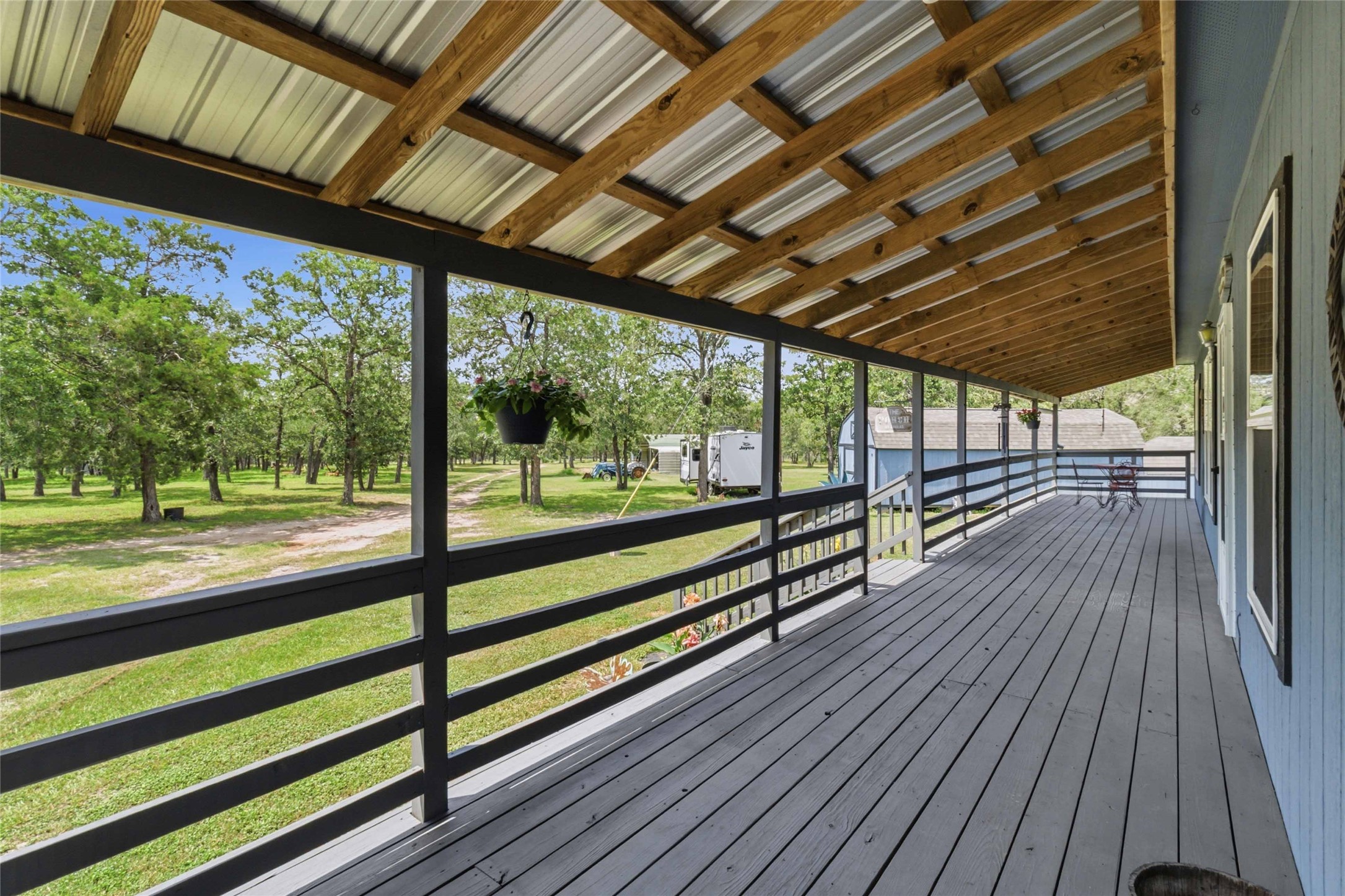 7921 Vista Ranch Road Smithville, TX 78957 - Photo 4 of 39 A spacious covered porch overlooks a verdant landscape, offering a serene outdoor living area.