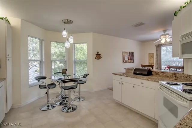 a view of a kitchen with kitchen island a large window cabinets a sink and stainless steel appliances