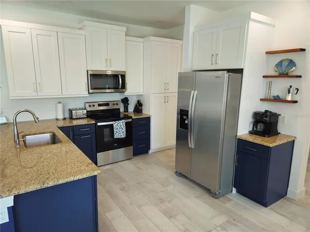 a kitchen with stainless steel appliances granite countertop a refrigerator a stove a sink and a refrigerator