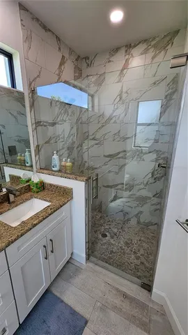 a bathroom with a granite countertop sink a mirror and shower